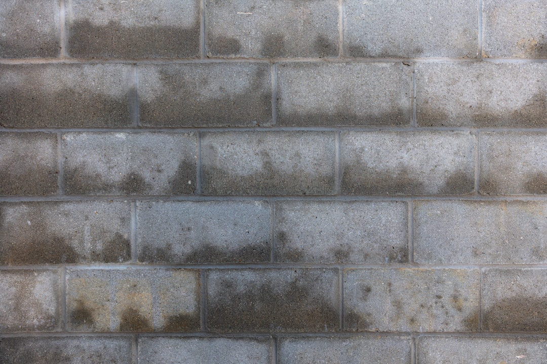 Maçon professionnel à Saint-Vit construisant mur porteur en parpaing avec outillage spécialisé
