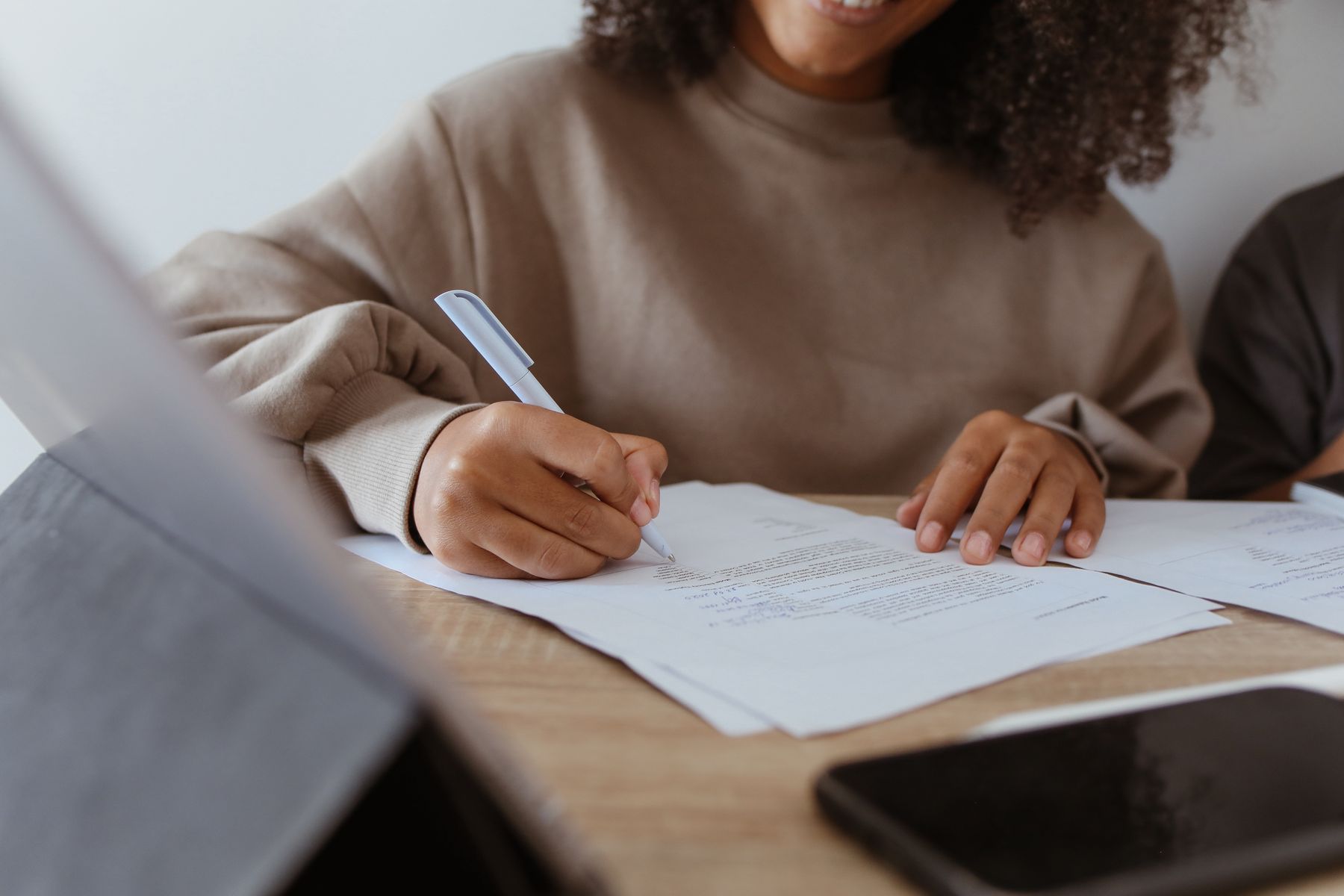 Personne lisant attentivement des conditions écrites avant de signer, stylo à la main