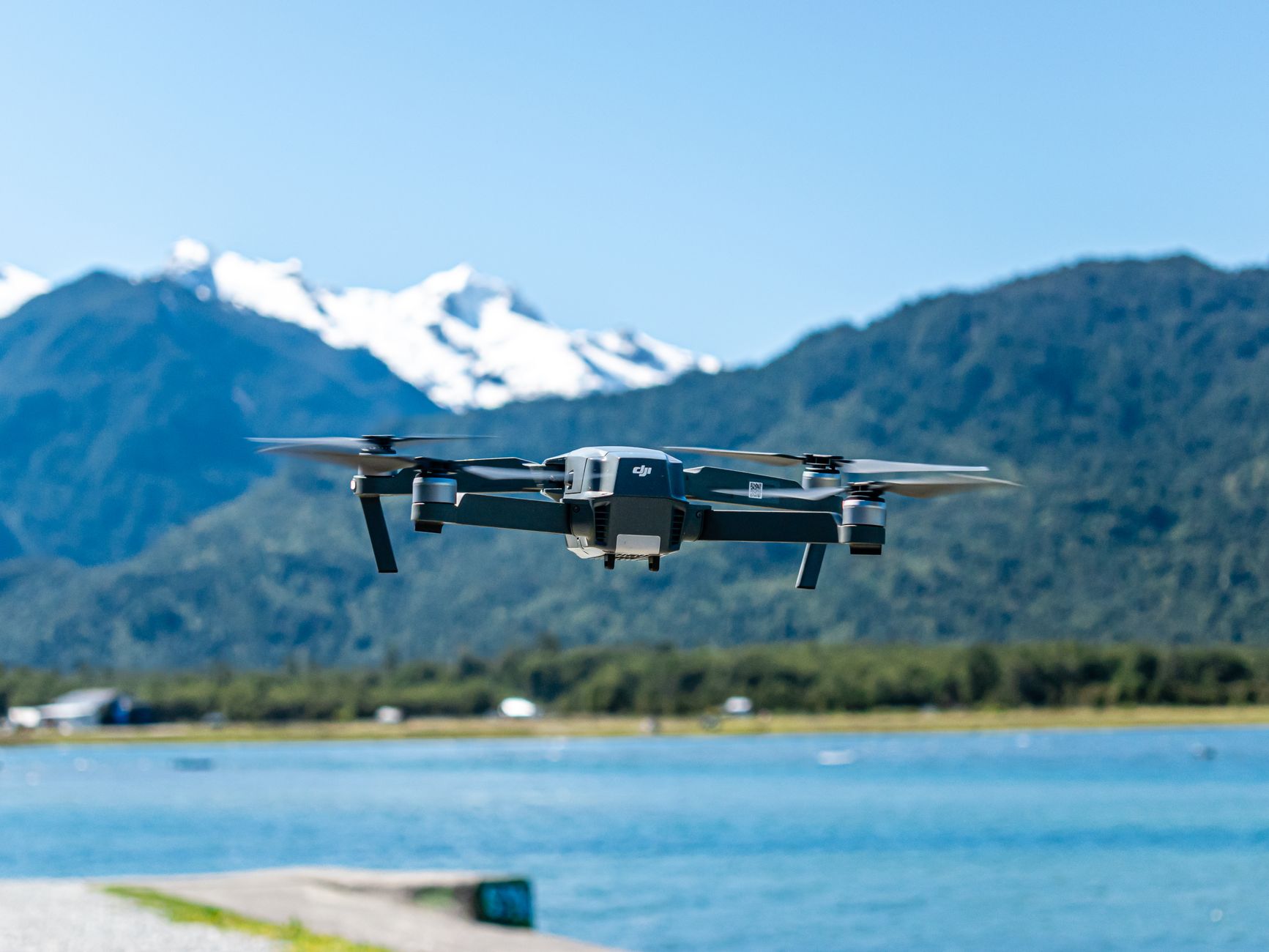 Drone en vol au-dessus d'un lac de montagne, sommets en arrière-plan