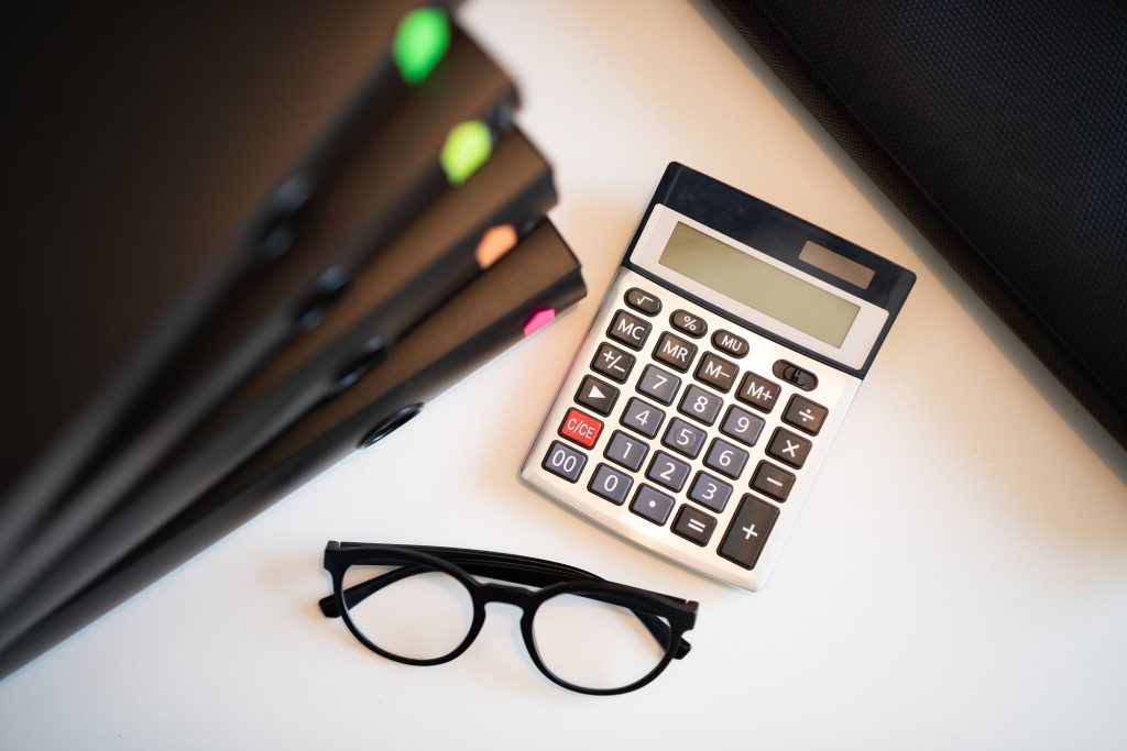 Calculatrice, lunettes et dossiers sur un bureau (taux d'interet legal)