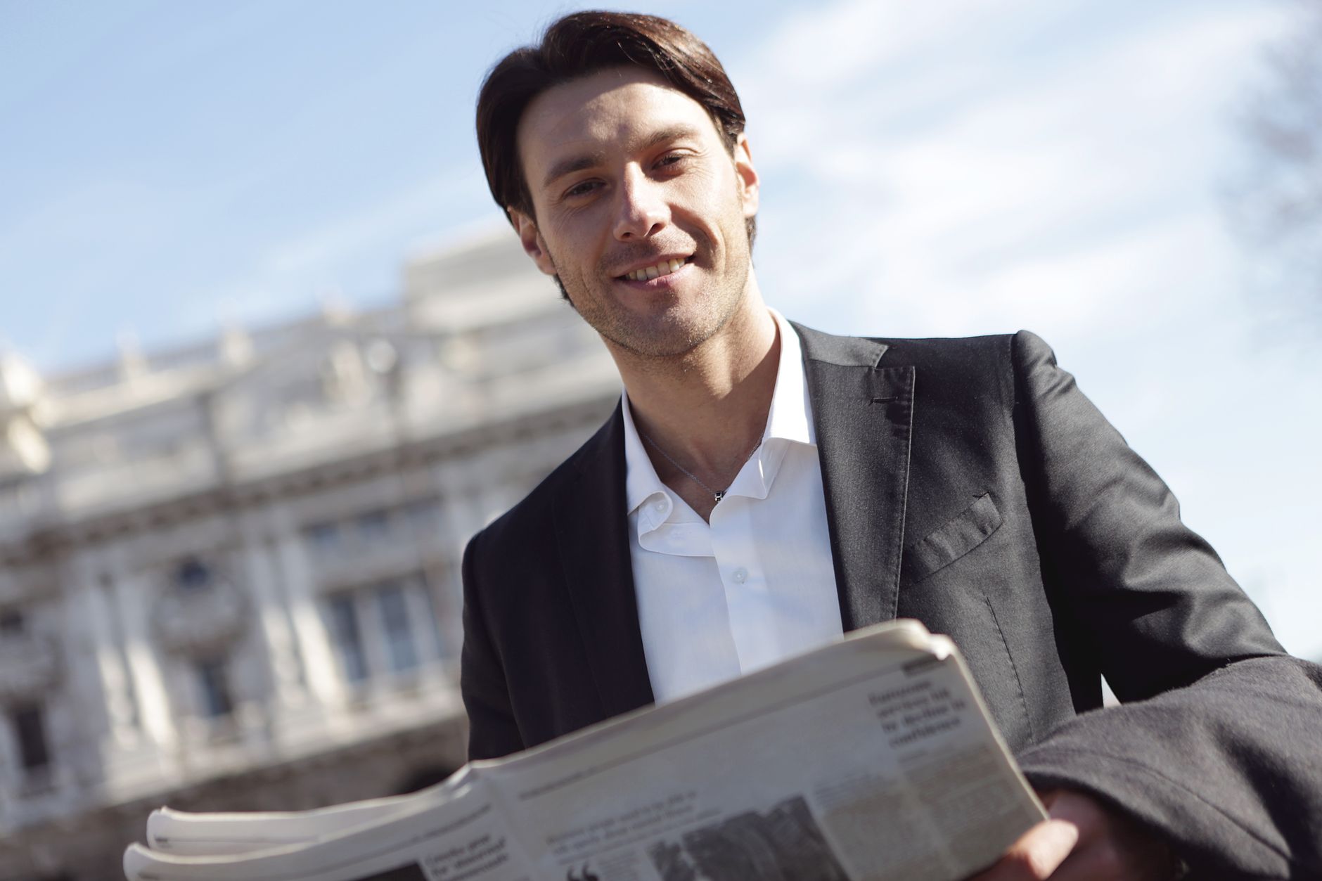 Un homme en costume lit un journal économique, illustration de la veille économique quotidienne d'un dirigeant