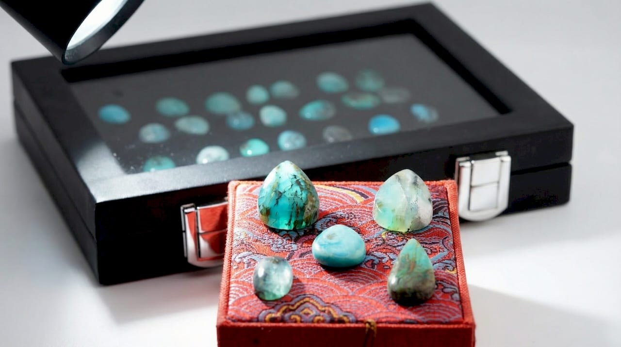 Cabochons d'opale bleue du Pérou polis en dôme posés sur un écrin rouge