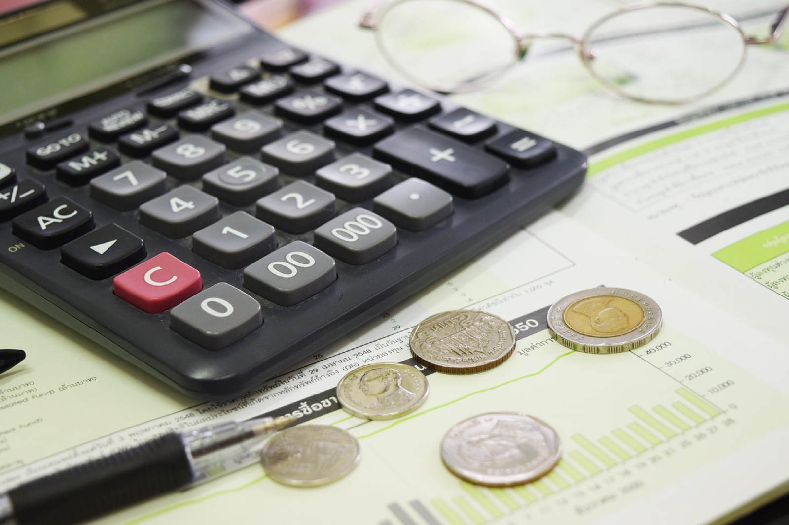 Calendrier, calculatrice et pièces sur un bureau pour planifier un budget